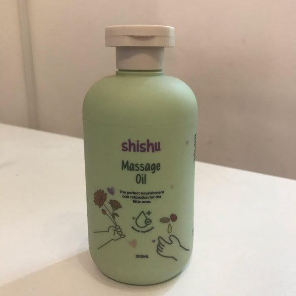 A bottle of Shishu Baby Massage Oil with a label that includes a drawing of a baby and some plants, indicating it is a skincare product for babies.