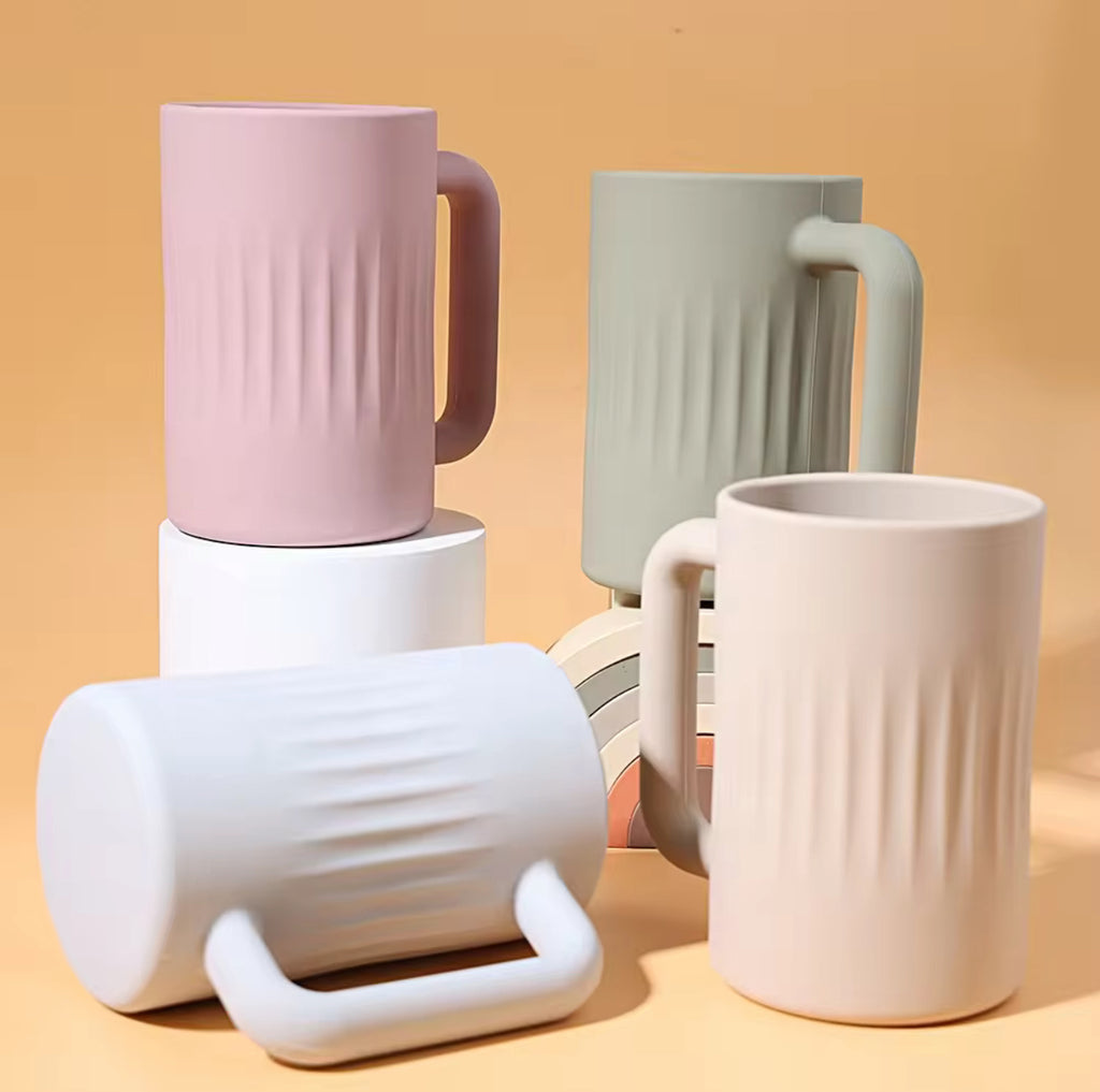 A set of silicone handled rinse cups in various colors including pink, gray, orange, and white, stacked together.