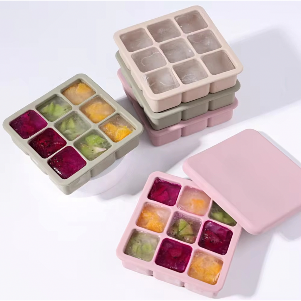 A stack of silicone ice cube trays with lids in various colors including beige and pink