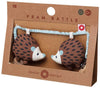 A packaged hedgehog-shaped pram rattle toy with brown, white, and dark gray colors, displayed in a clear plastic front box with a cardboard backing.