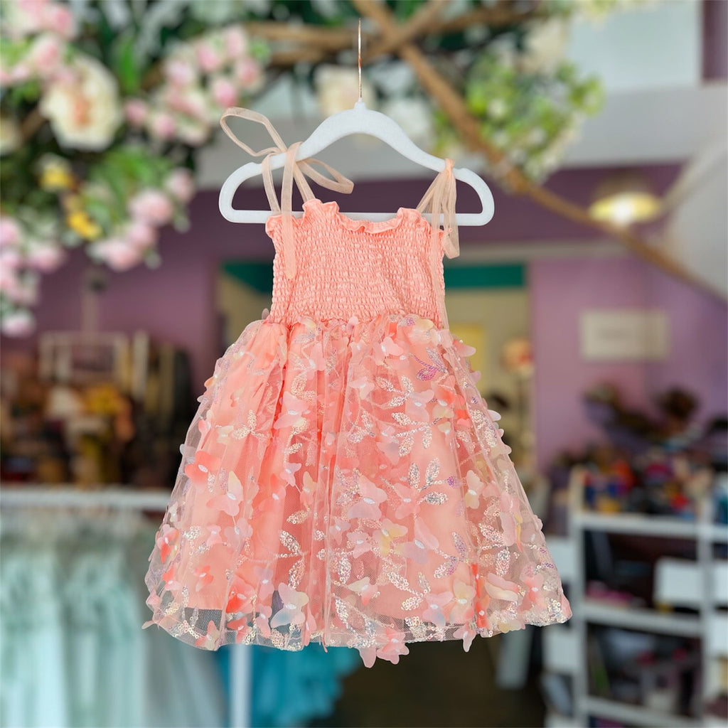 Pink floral dress on a hanger with a blurred store background