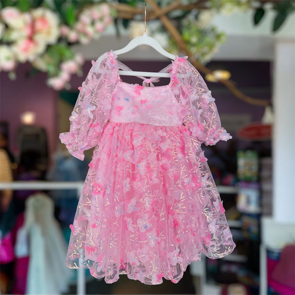 Pink floral dress on a hanger with a blurred indoor background