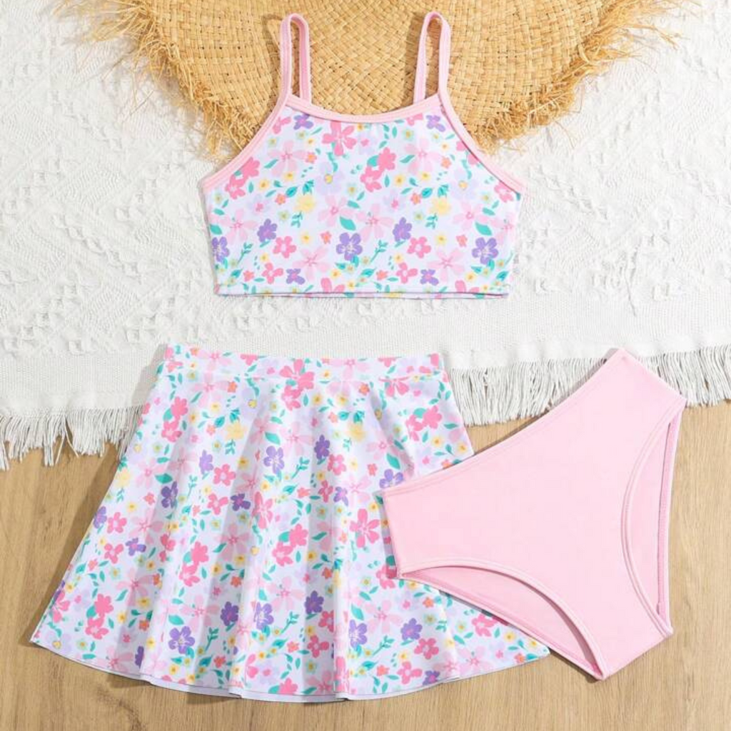 A three piece pink floral swimsuit with a skirt, consisting of a pink floral tank top, a pink floral skirt, and a pink swim skirt.
