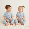 Two children wearing matching pajamas with a cat pattern on a white background