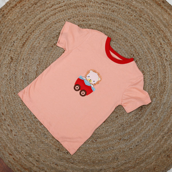 Pink t-shirt with a teddy bear design on a textured surface