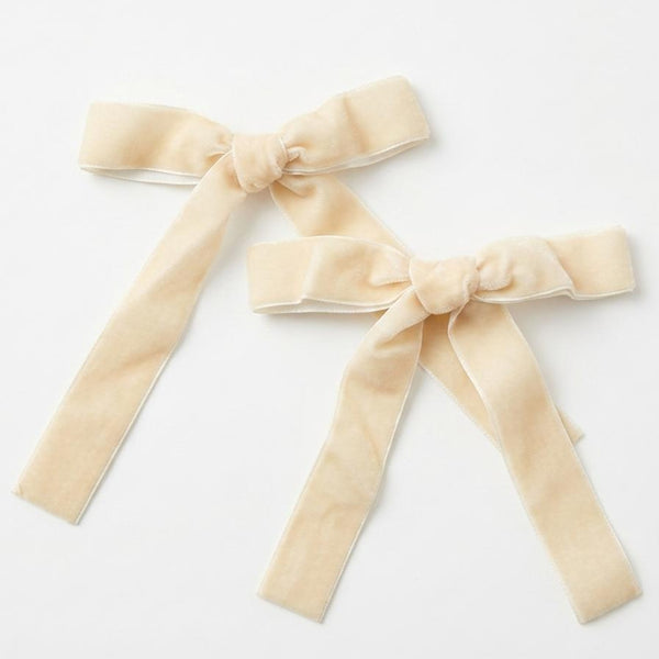 Two beige velvet bows on a white background