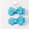 Two blue hair bows on a white card with a bow design.