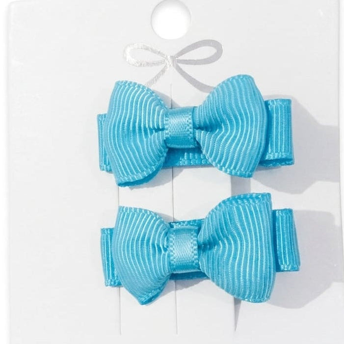 Two blue hair bows on a white card with a bow design.