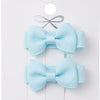 Two light blue hair bows on a white card with a gray ribbon.
