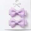 Two purple hair bows on a white card with a white background