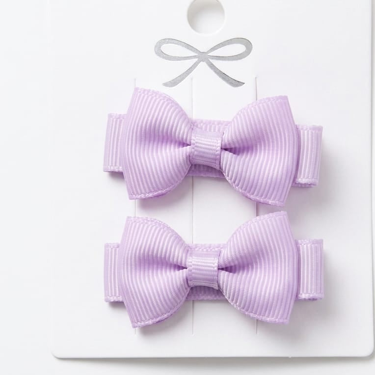 Two purple hair bows on a white card with a white background