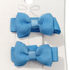 Two blue hair bows on a white card with a decorative bow design.