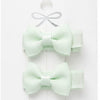 Set of three light green hair bows in packaging on a white background