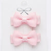 Two pink hair bows on a white card with a gray ribbon.