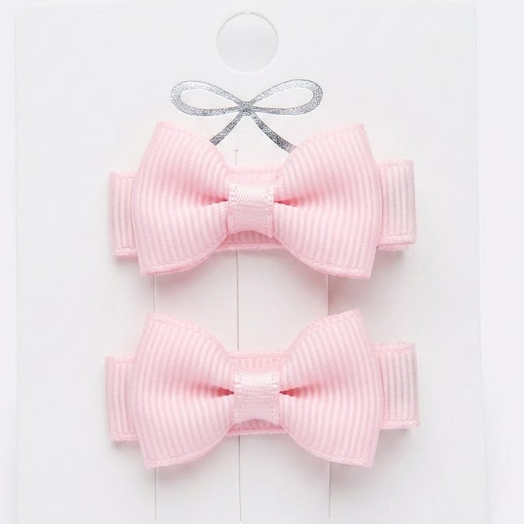 Two pink hair bows on a white card with a gray ribbon.
