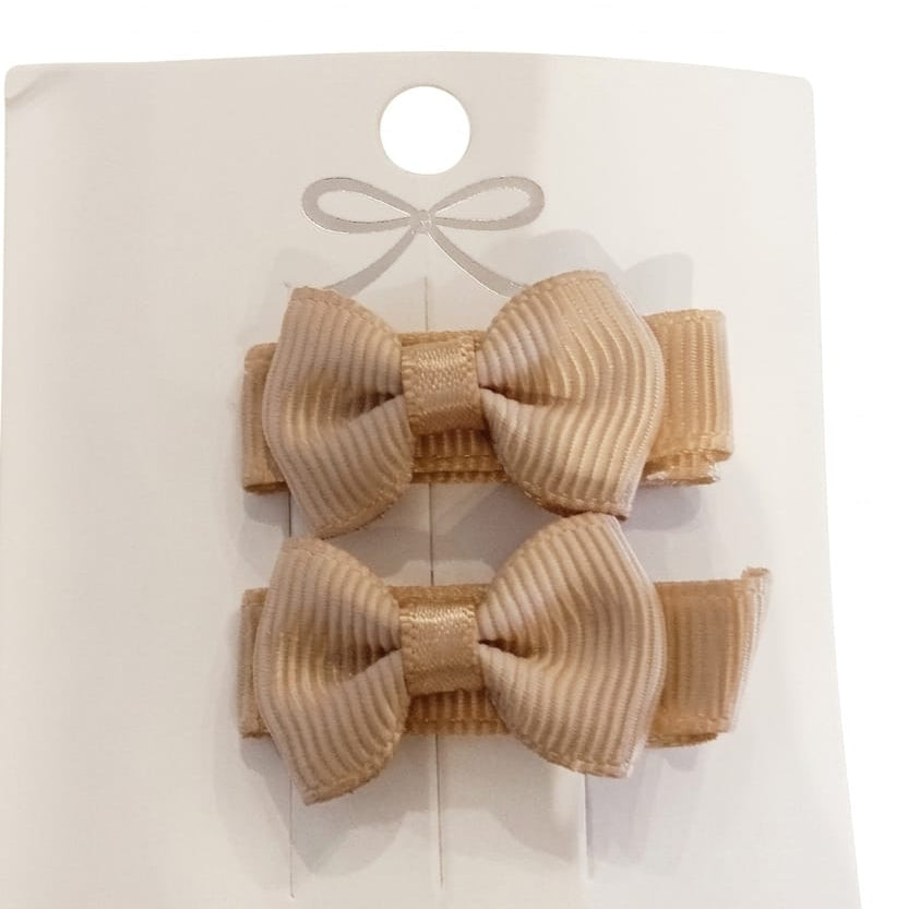 Two beige hair bows on a white card with a ribbon