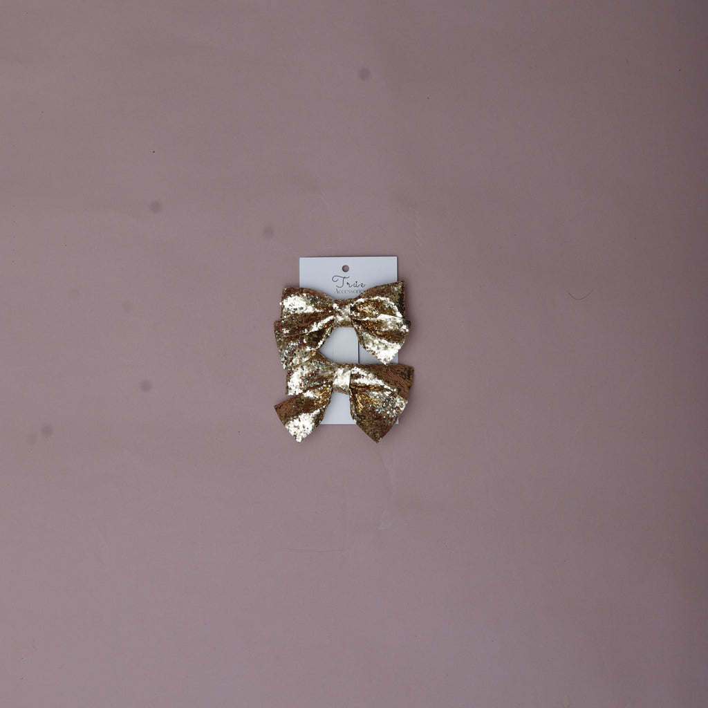 Gold hair clip on a small white card against a pink background