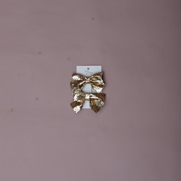 Gold hair clip on a small white card against a pink background