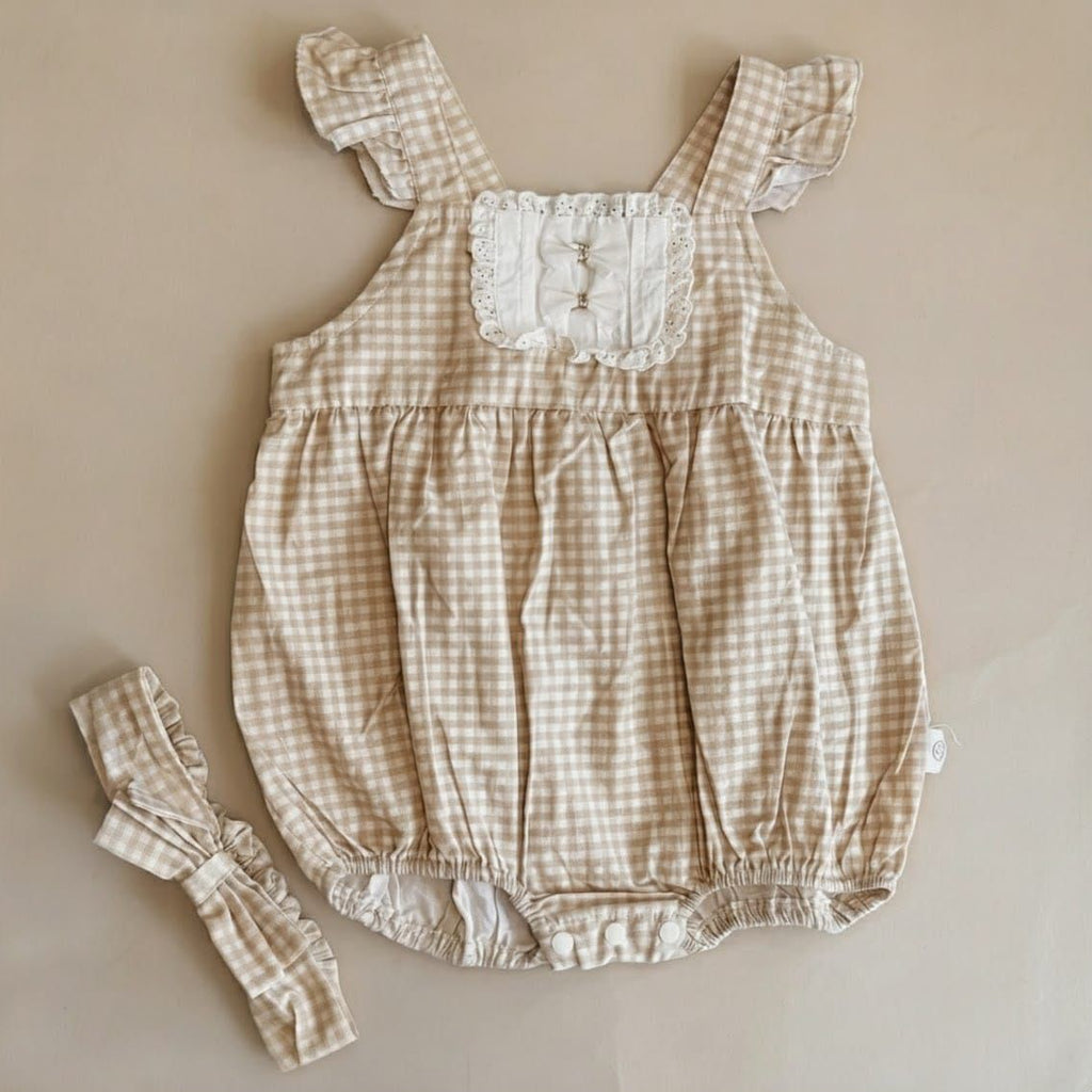 Beige checkered baby romper with matching headband on a beige background