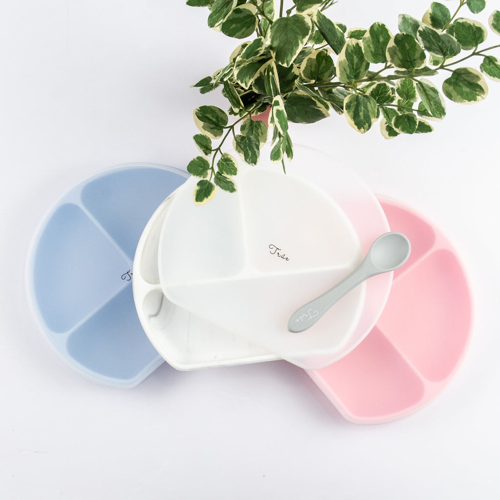 Three True Silicone Divided Smile Plates with Lid, in pastel colors of blue, white, and pink. These BPA-free, food-grade silicone plates are perfect for mealtime. 